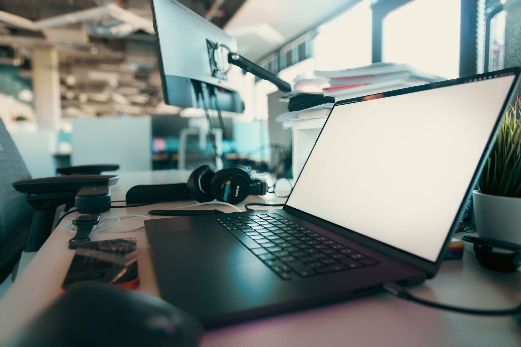 Modern office workspace with a laptop, monitor and headphones